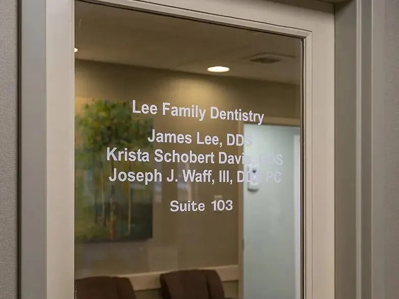 The glass door of Suite 103, lettered with Lee Family Dentistry and the names of Dr. James Lee, Dr. Krista Schobert Davis and Dr. Joseph J. Waff III.