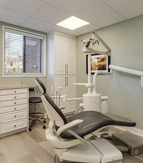 A treatment room with a window, a chair-side monitor and white cabinetry.