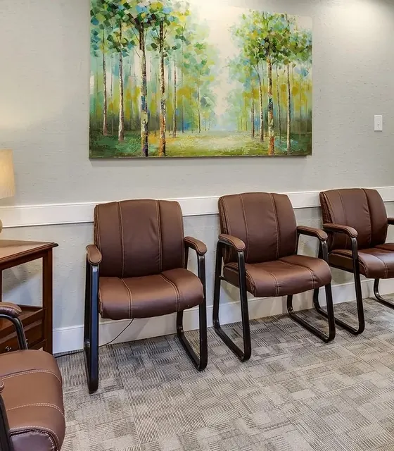 The waiting room, with leather chairs and a painting of birch trees.