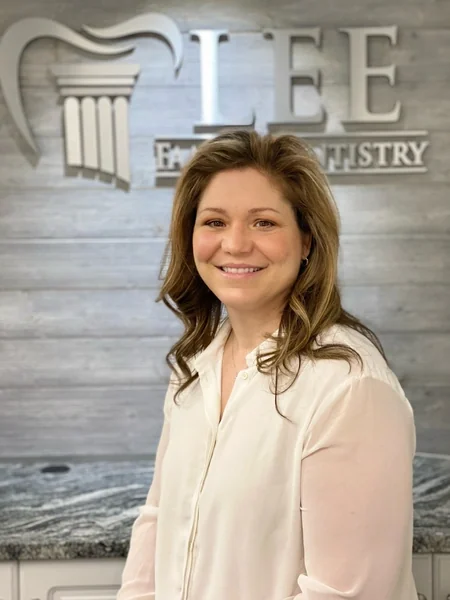 April, of the Lee Family Dentistry team, in front of the office sign.