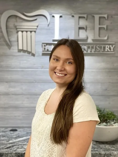 Elizabeth, of the Lee Family Dentistry team, in front of the office sign.