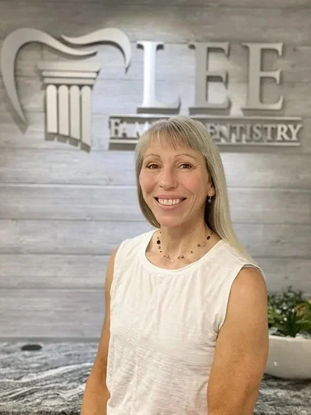 Jodi, of the Lee Family Dentistry team, in front of the office sign.