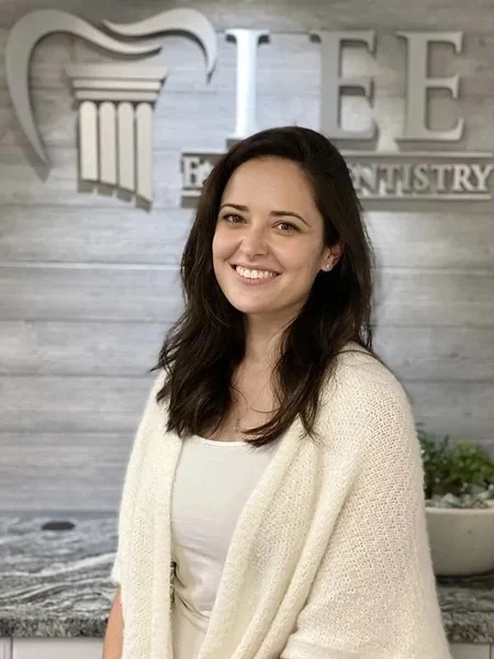 Kristen, of the Lee Family Dentistry team, in front of the office sign.
